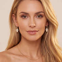 Gold hamsa drop earrings worn, dangling hand charm with blue eye and stones