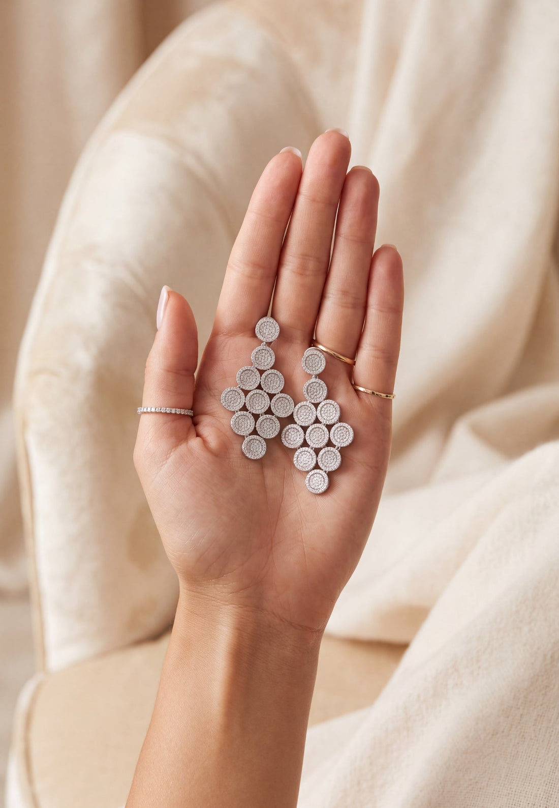 Silver disc cascading drop earrings shown in hand, with stacked circular drops