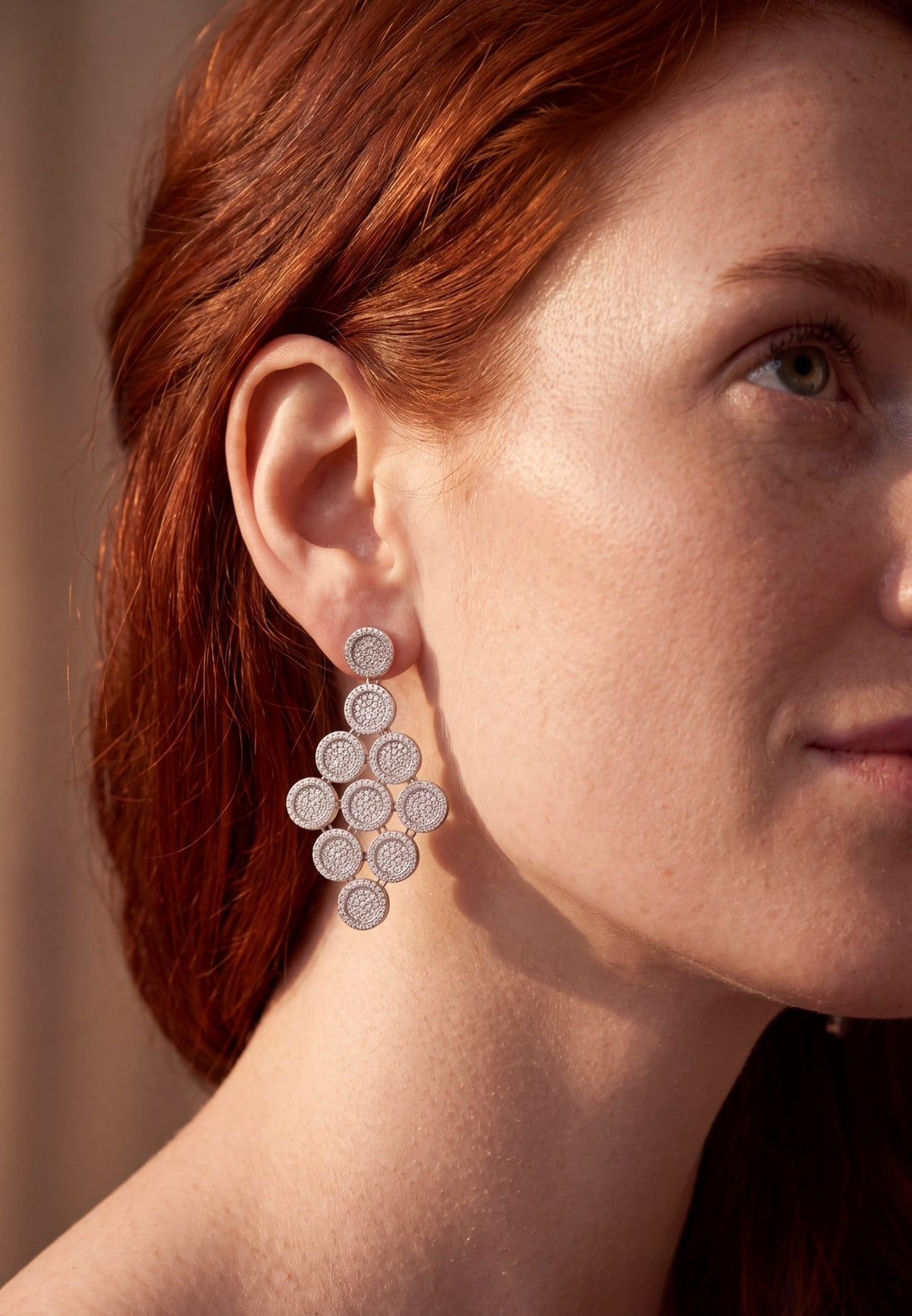 Silver disc cascading drop earrings worn on a model&