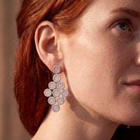 Silver disc cascading drop earrings worn on a model's ear