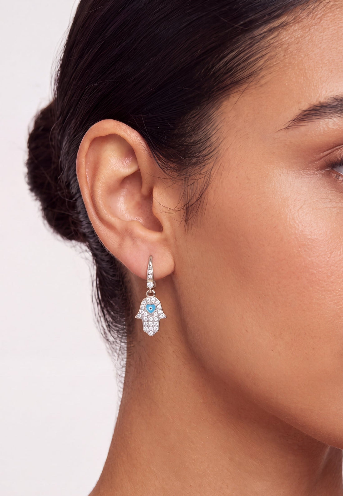 Silver-tone hamsa drop earring with blue enamel eye charm and crystal stones.