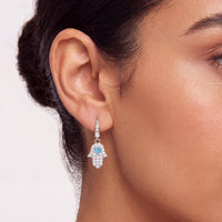 Silver-tone hamsa drop earring with blue enamel eye charm and crystal stones.