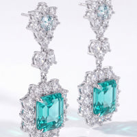 Close-up silver drop earrings with teal emerald-cut center stones and crystals