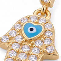 Close-up gold hamsa hand charm with blue eye enamel and clear rhinestones