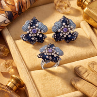 Blue orchid flower stud earrings with purple center stones on jewelry display box.