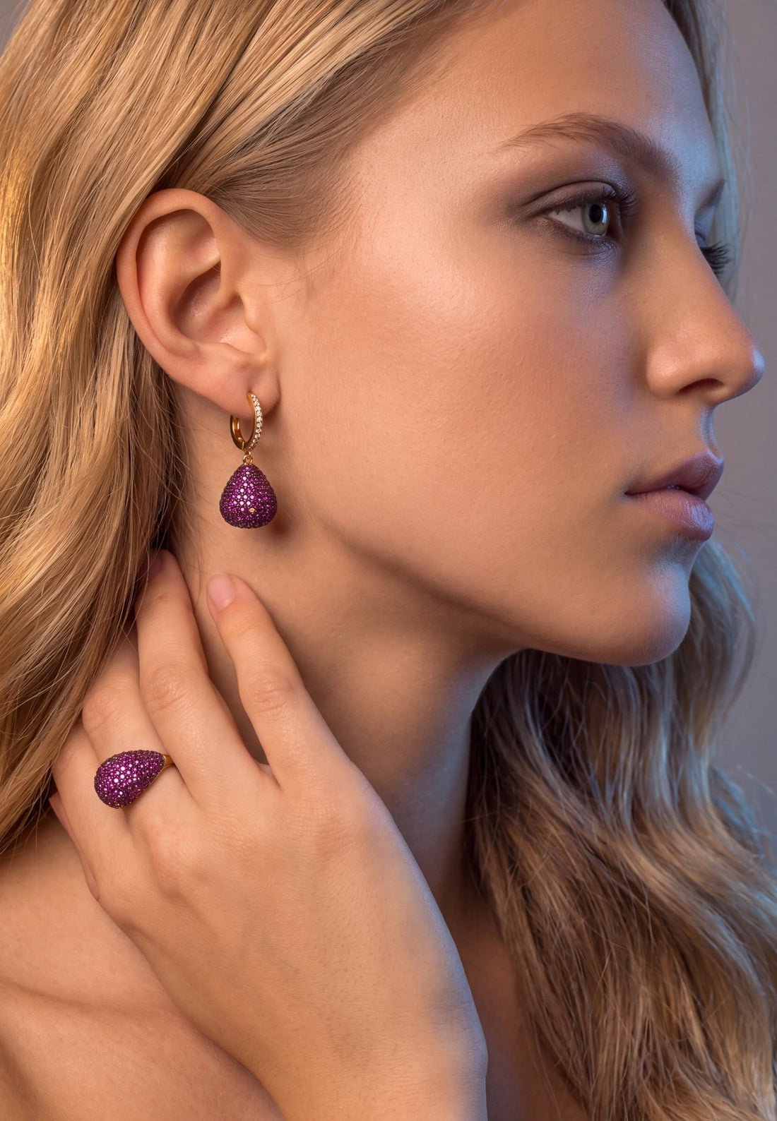 Gold pear-drop gemstone earrings with purple teardrop crystals and hinged hook