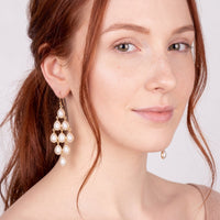 Pearl chandelier drop earrings with gold hooks, worn by model