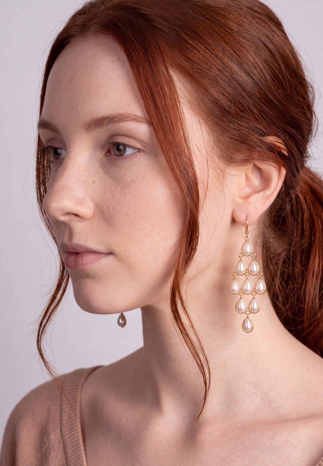 Pearl drop chandelier earrings on gold hooks, worn by model