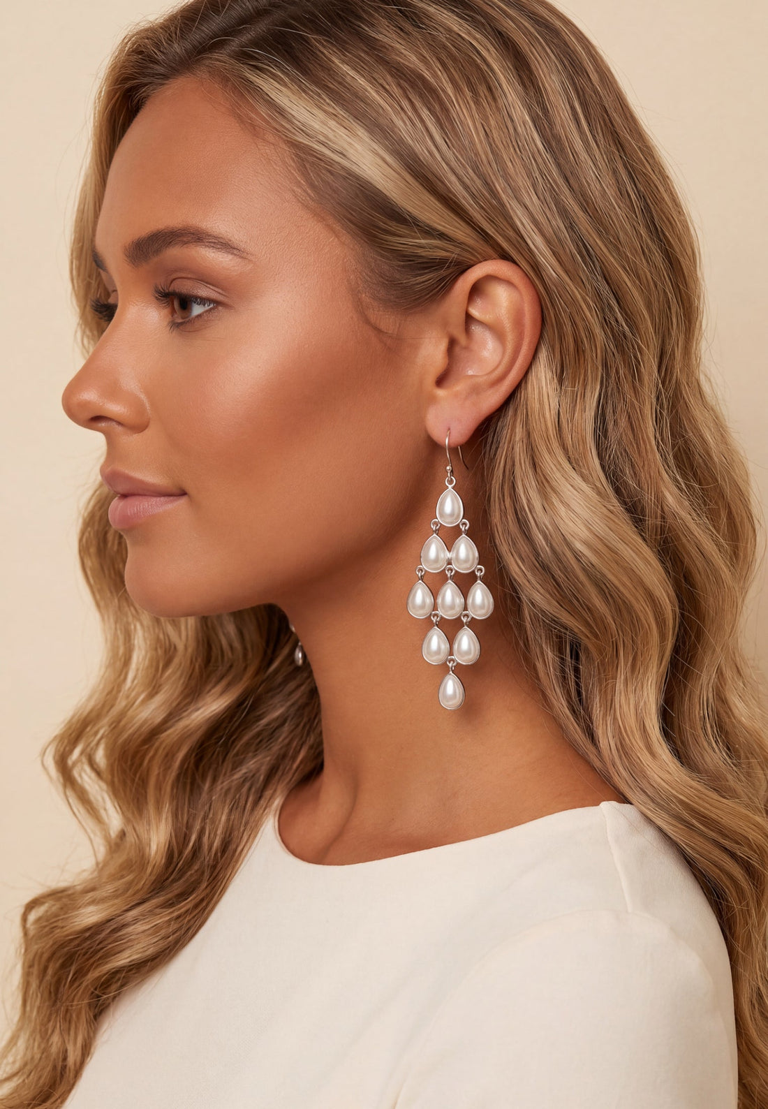 Silver-tone pearl teardrop chandelier earrings dangling from ear, side view