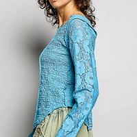 Teal blue lace long-sleeve top with round neck and exposed seams, side view