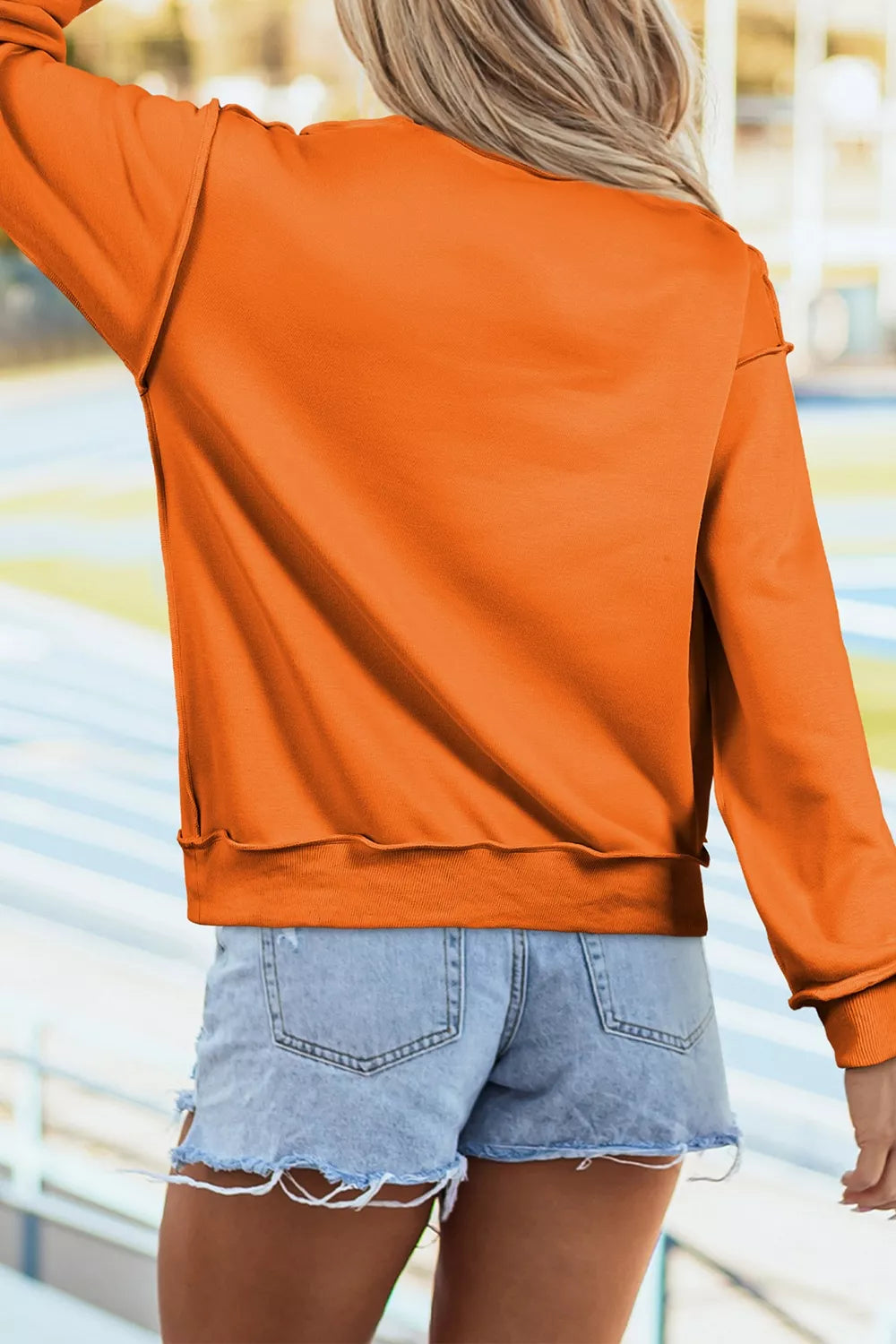 Orange mock neck sweatshirt back view with curved hem and ribbed cuffs