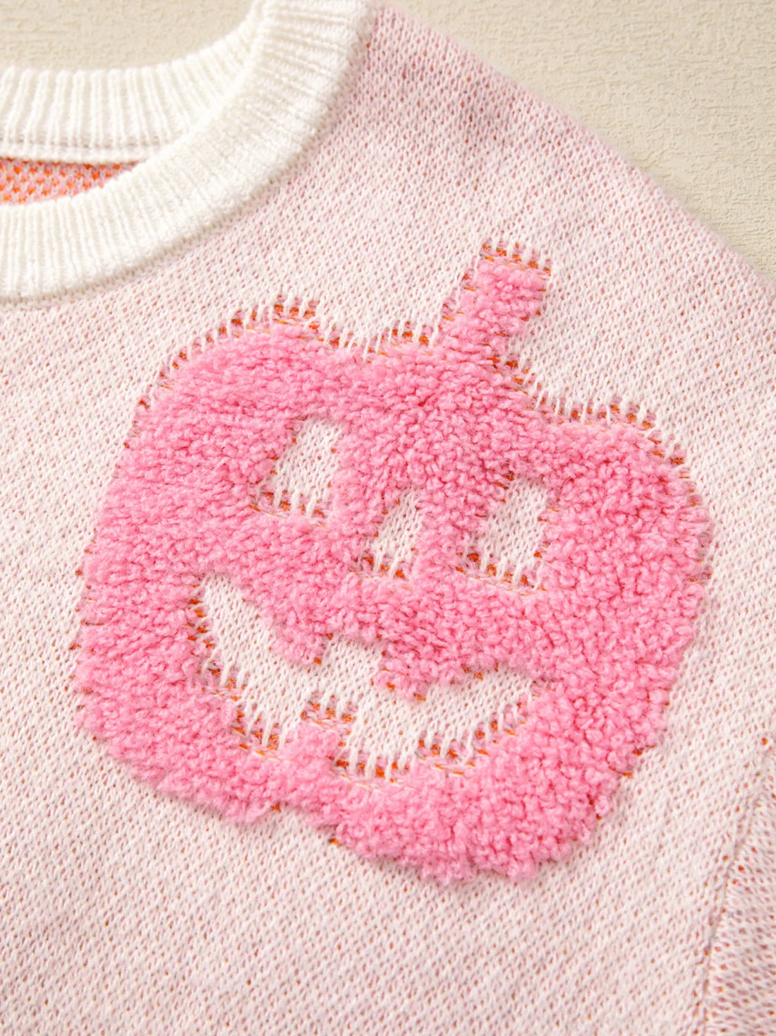 Dusty pink knit sweater with a pink pumpkin patch and ribbed white neckline