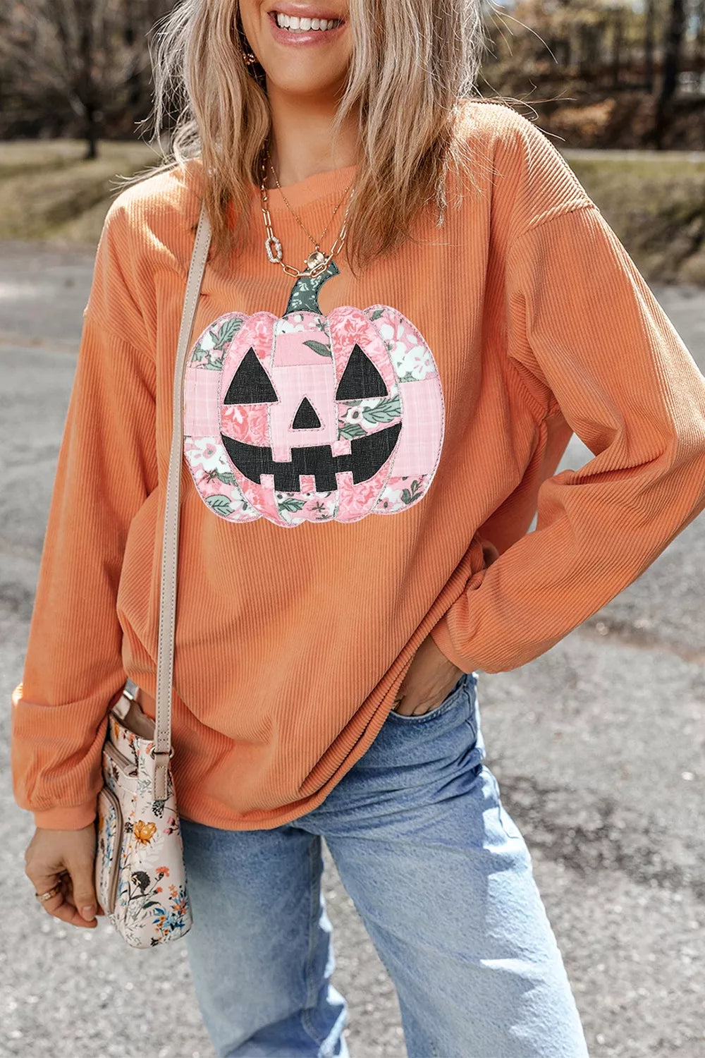 Orange sherbet tunic sweatshirt with long sleeves and patchwork pumpkin face graphic