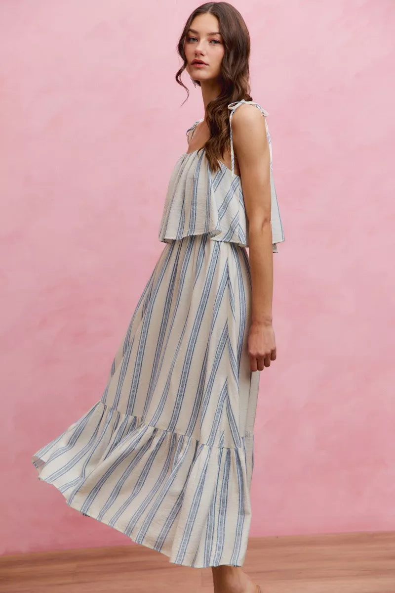 Front three-quarter view of sleeveless vertical stripe midi dress with tiered ruffle skirt