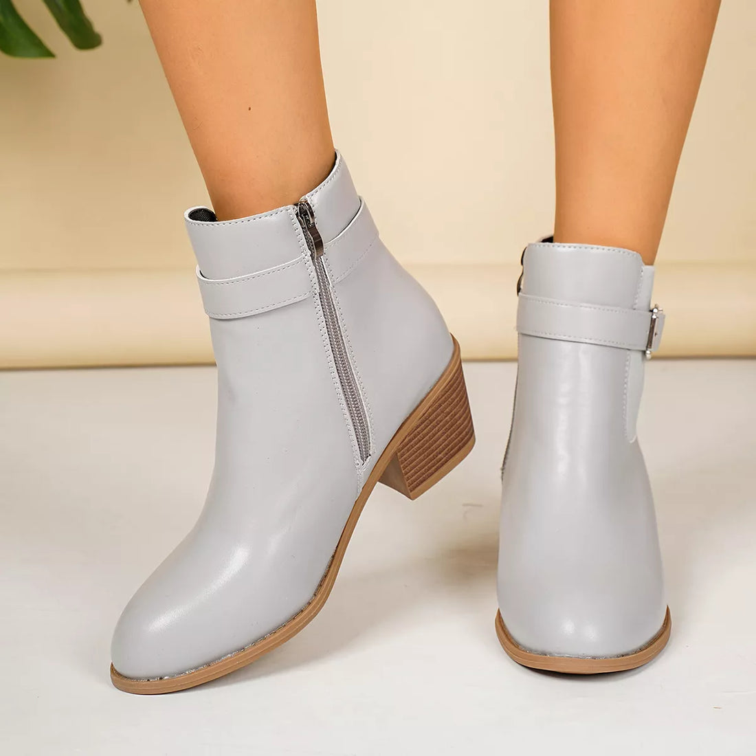 Light gray point-toe block heel ankle boots with front buckle straps