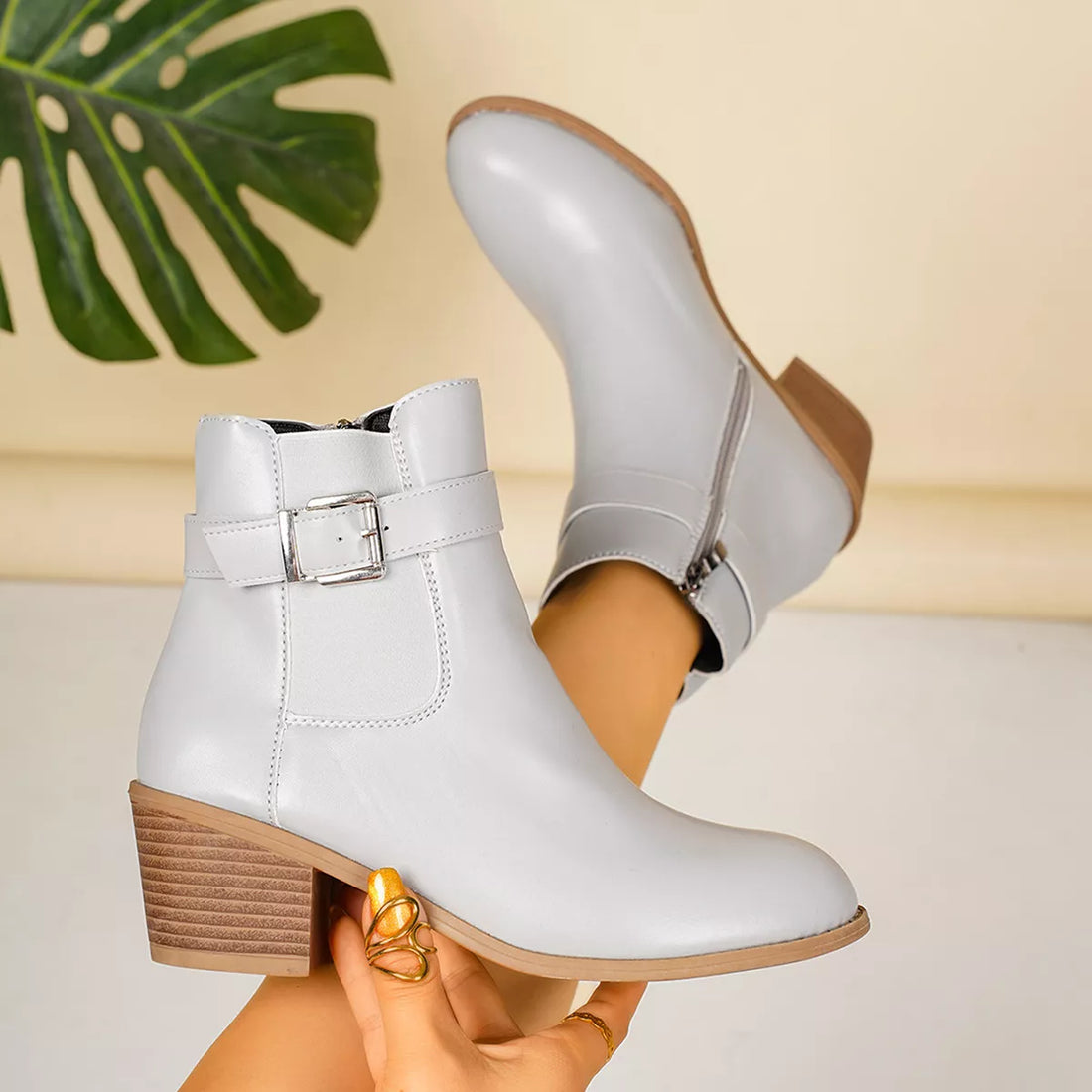 Light gray point-toe block heel ankle boots with front buckle and side zip
