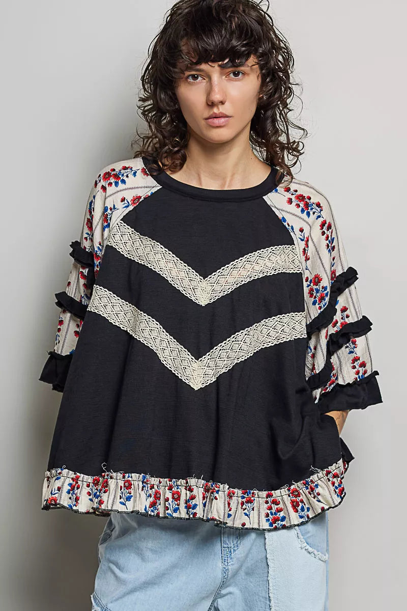 Black oversized knit top with round neck, contrast chevron lace, floral ruffle trims