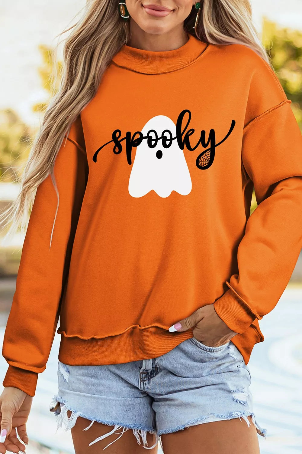 Orange mock neck sweatshirt with white ghost graphic and black lettering