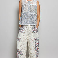 Off-white sleeveless lace round-neck top with blue floral print and scalloped edges