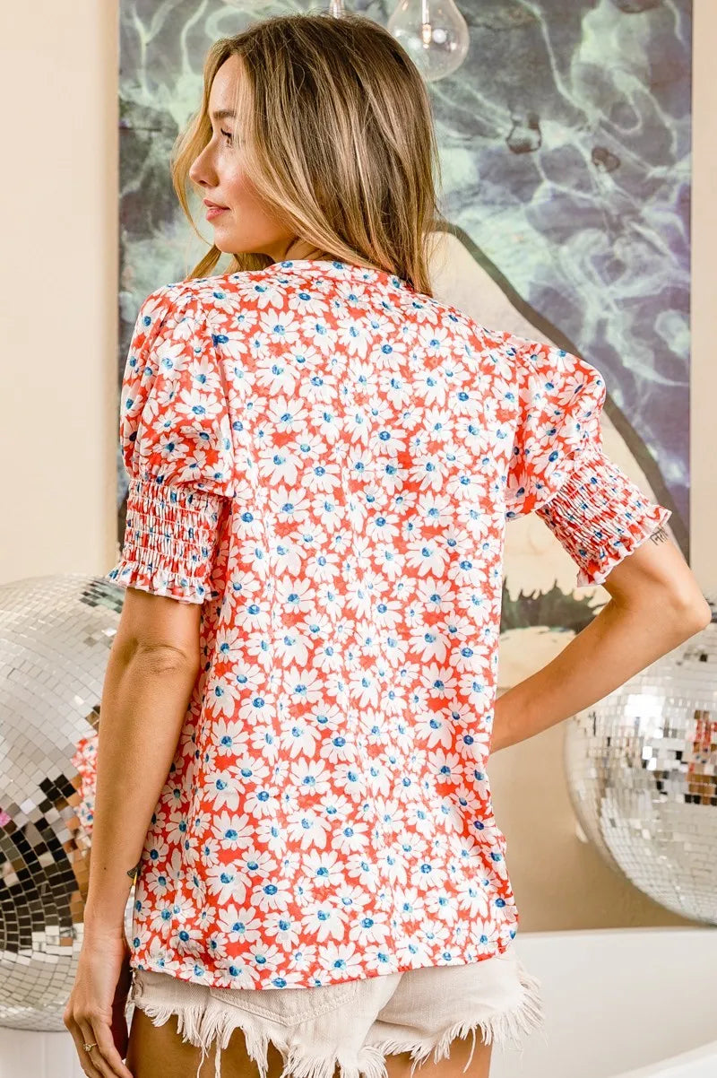 Orange floral V-neck top back view with smocked puff sleeves and gathered shoulders