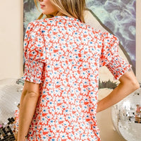 Orange floral V-neck top back view with smocked puff sleeves and gathered shoulders