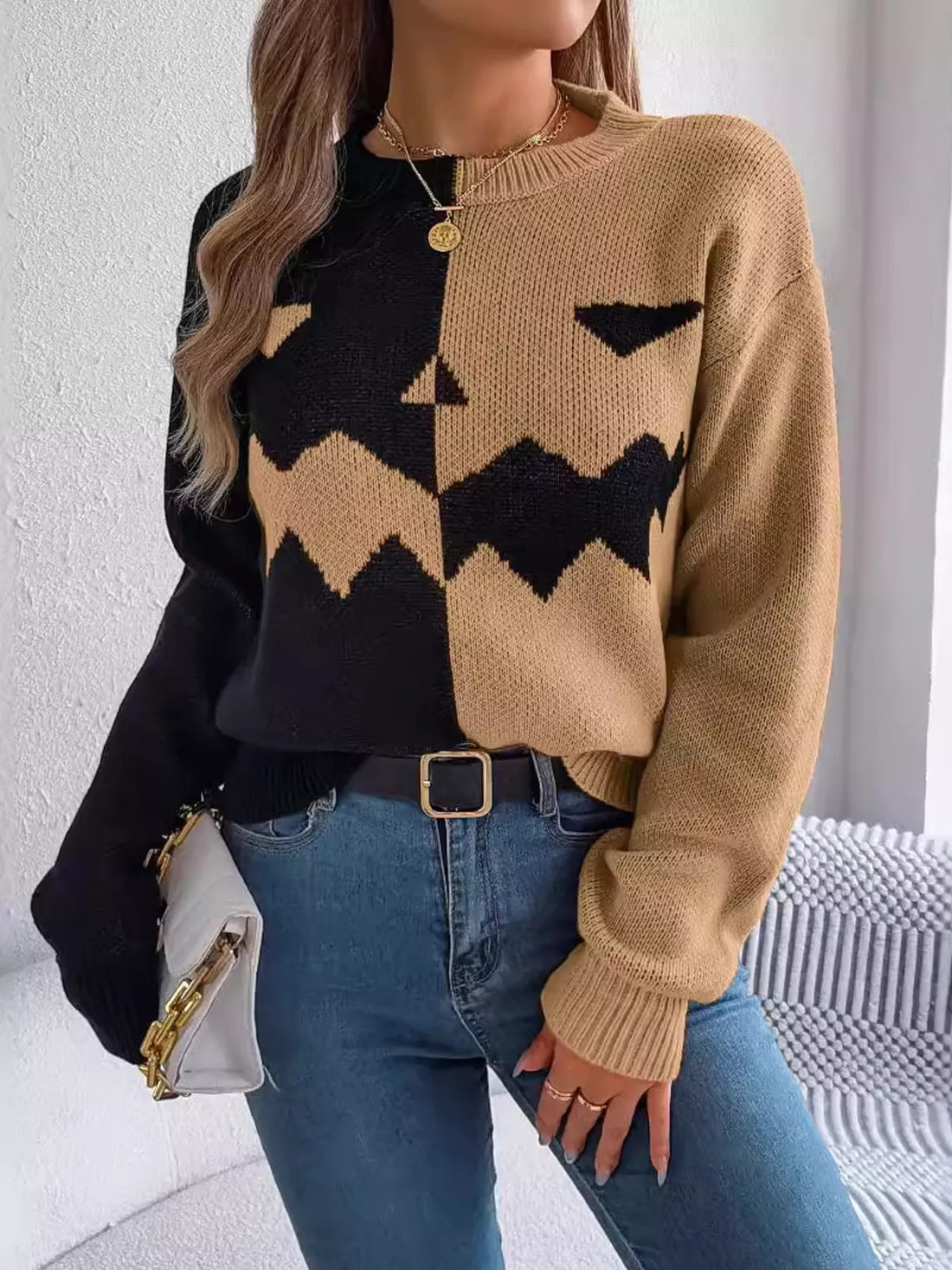 Long-sleeve two-tone knit sweater with pumpkin-face graphic, camel and black.