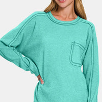 Turquoise knit top with contrast stitching on chest pocket and ribbed crew neck