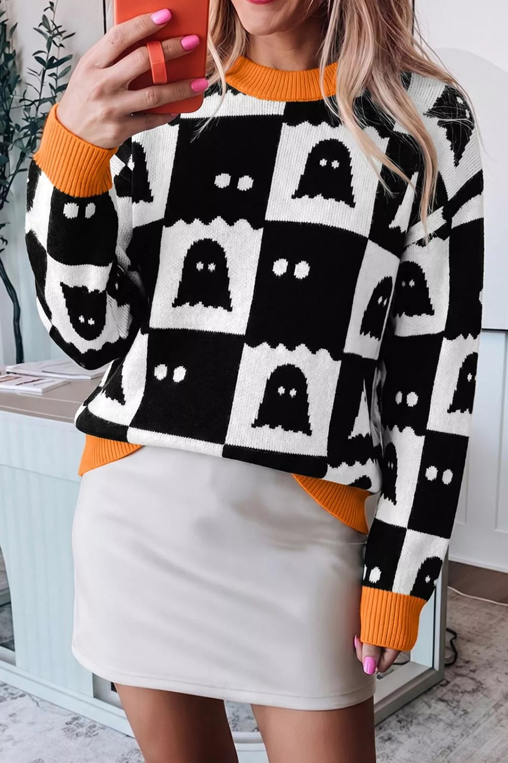 Ghost face checkerboard sweater in black and white with orange ribbed crew neck