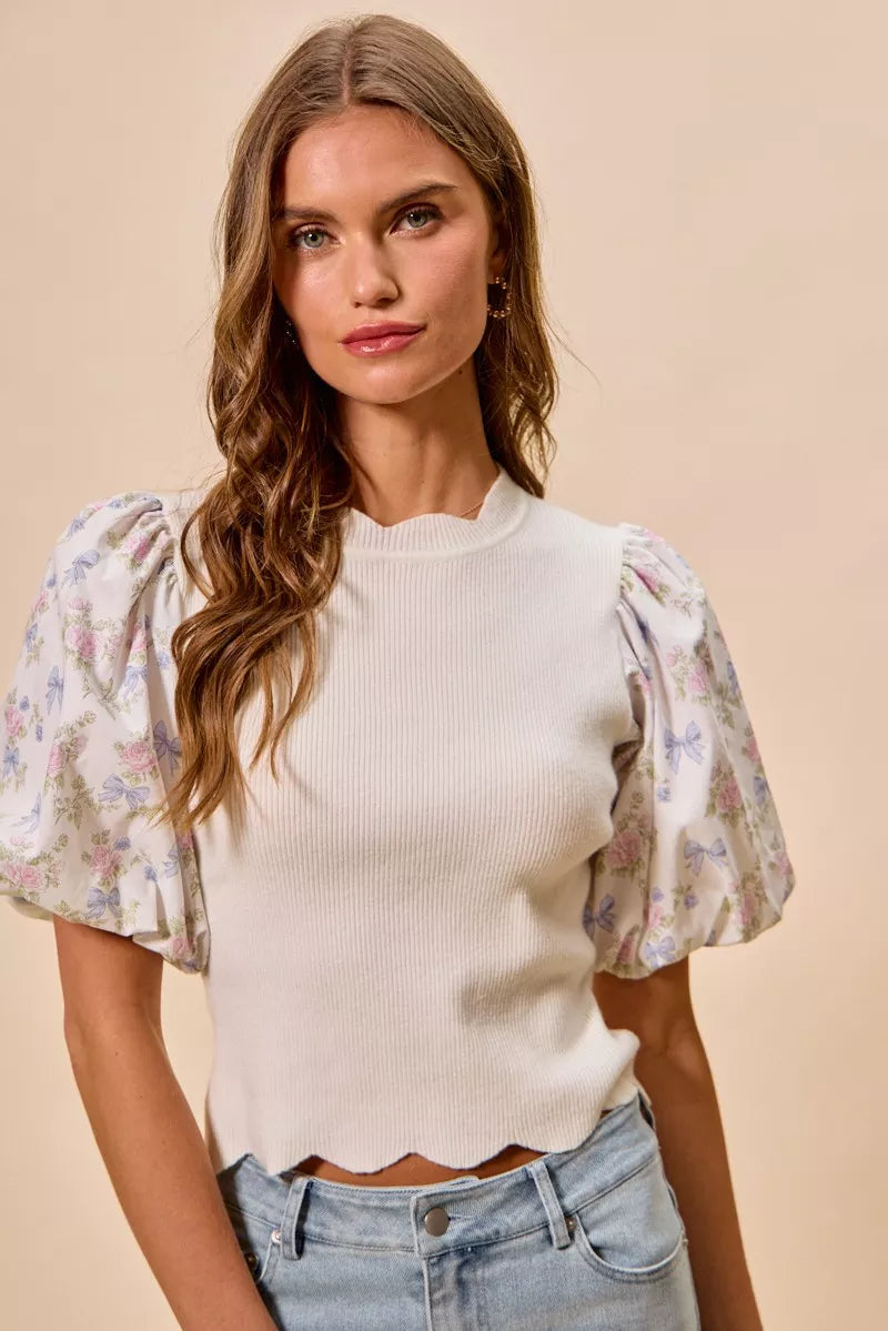 White sweater top featuring short floral puff sleeves with scalloped hem