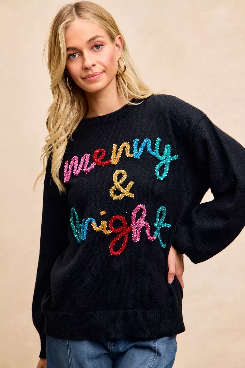 Black Christmas sweater showing multicolor "Merry & Bright" tinsel lettering on chest
