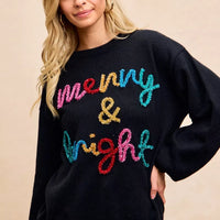 Black Christmas sweater showing multicolor "Merry & Bright" tinsel lettering on chest