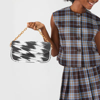 Small black and white patterned shoulder bag held by gold chain with white strap
