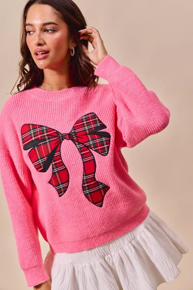 Pink ribbed sweater with oversized red plaid bow graphic and long sleeves