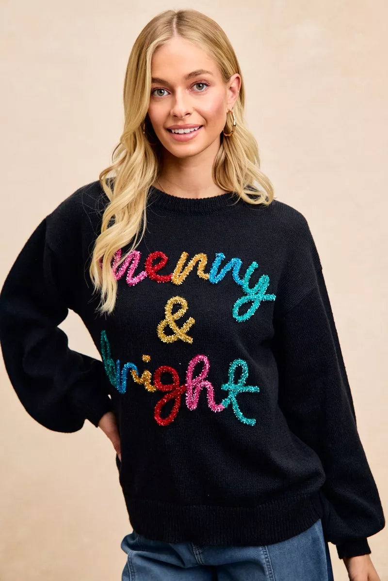 Black crewneck sweater with multicolor tinsel "Merry & bright" lettering, long sleeves.