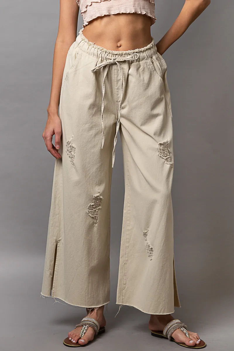 Cream distressed wide-leg pants with drawstring waist and side slit hem