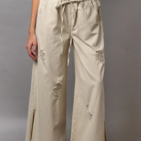 Cream distressed wide-leg pants with drawstring waist and side slit hem