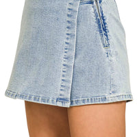 Light wash denim skort with wrap front, button closure, and utility pocket detail