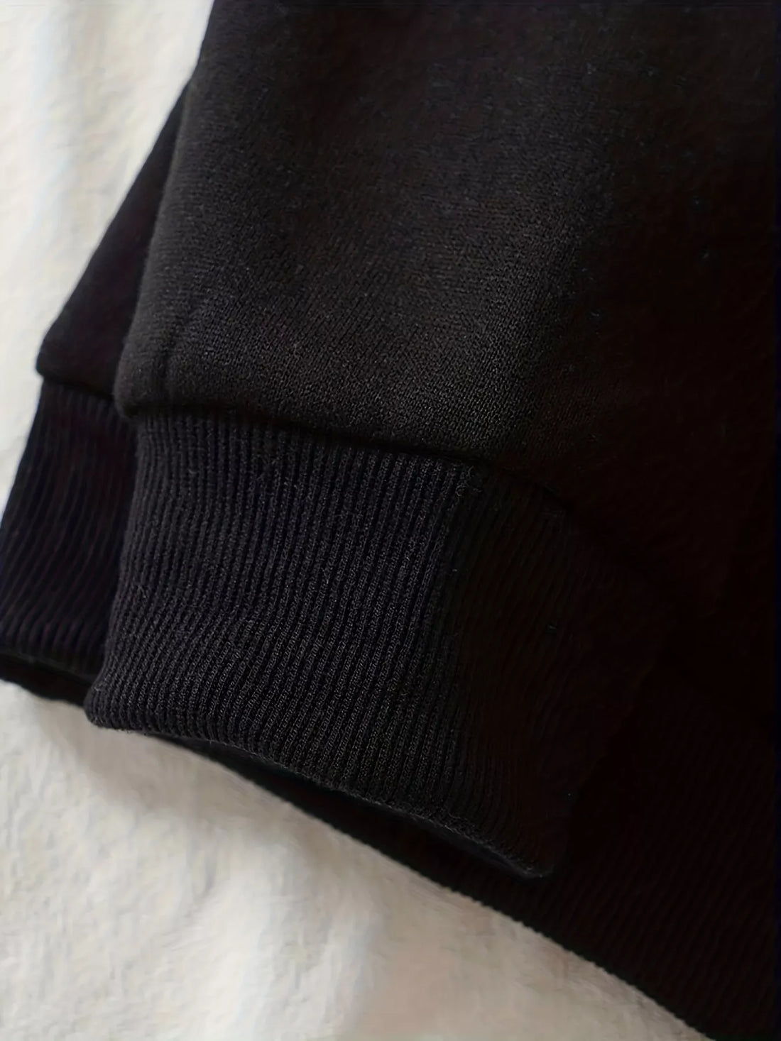 Black hoodie sleeve cuff and hem detail with ribbed knit finish