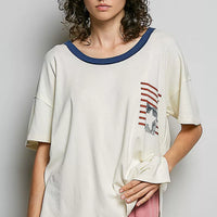 Cream cotton top with blue crew neckline trim and American flag graphic on chest