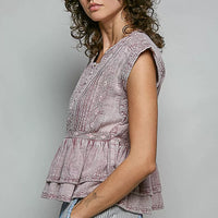 Pink sleeveless embroidered peplum blouse with button placket and layered ruffle hem.