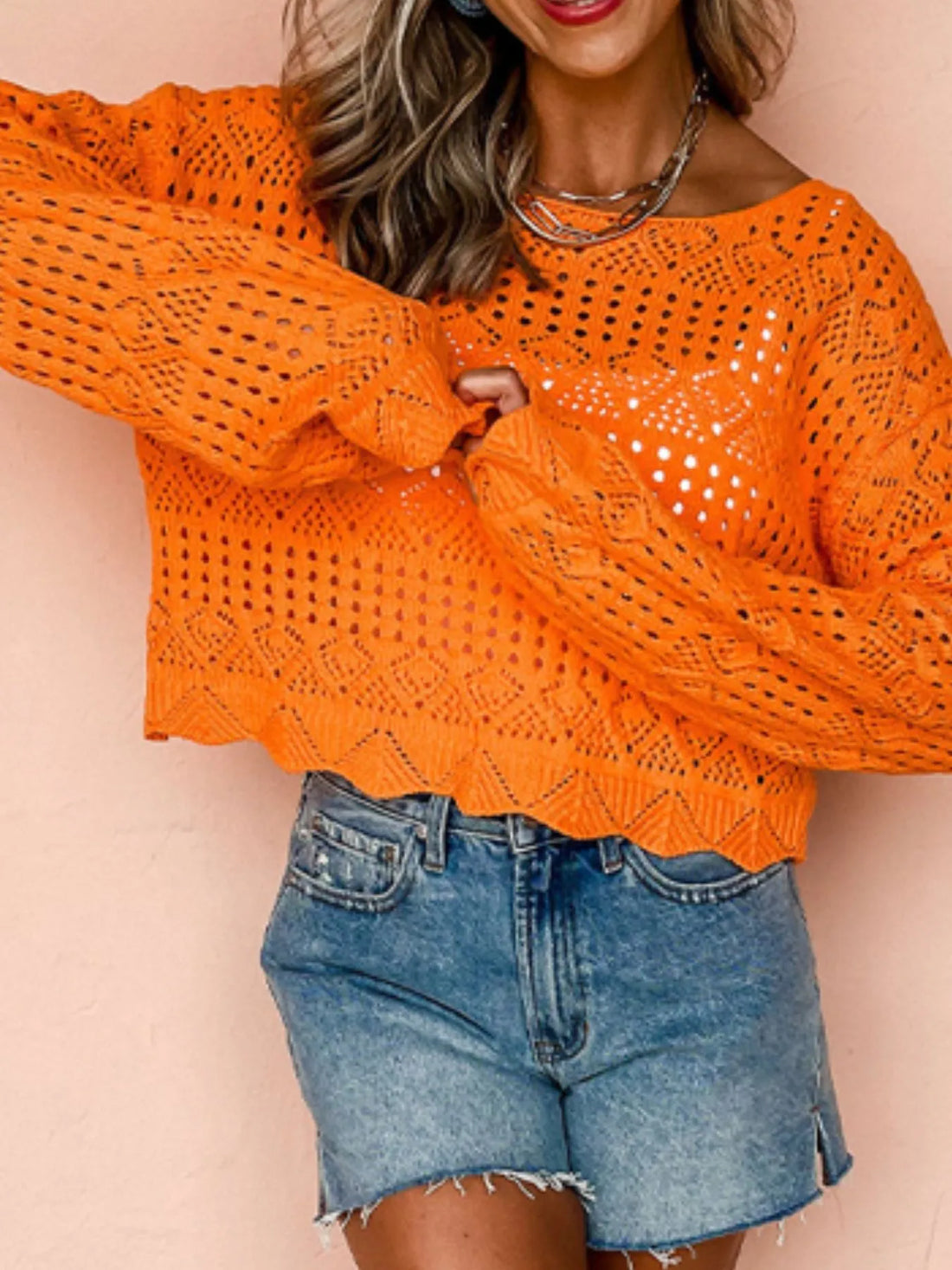 Orange knit cover-up with openwork crochet texture, boat neckline, and long loose sleeves