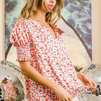 Orange floral V-neck top with smocked puff sleeves and short ruffled hem