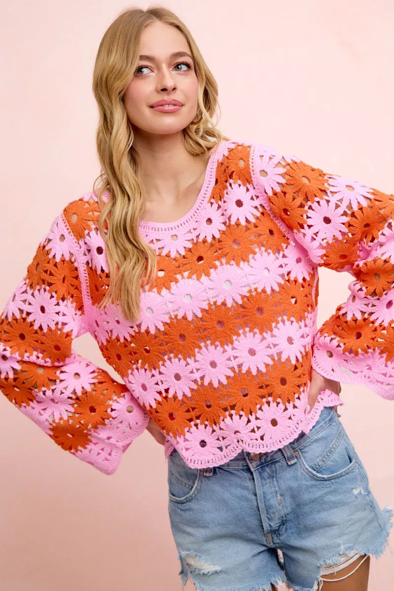 Orange crochet knit top with pink flower pattern, long sleeves, scoop neck hem detail.