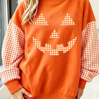 Orange pullover sweatshirt with checkered plaid sleeves and pumpkin face graphic