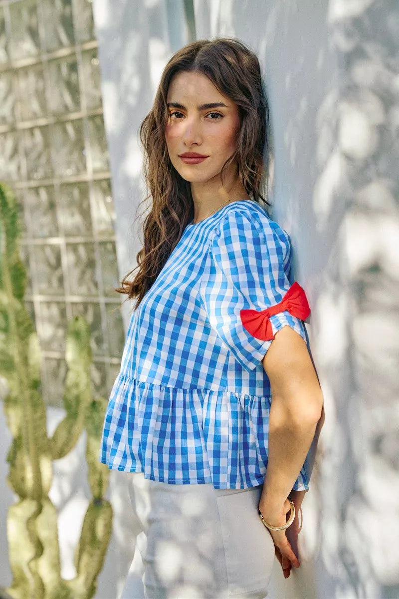 Blue gingham short-sleeve blouse with red ribbon bow shoulder detail and peplum hem