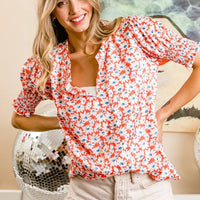 Orange floral V-neck top with puff sleeves and smocked detail, ruffled short hem