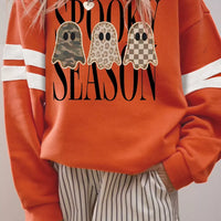 Orange sweatshirt with ghost trio graphic and white striped sleeve cuffs