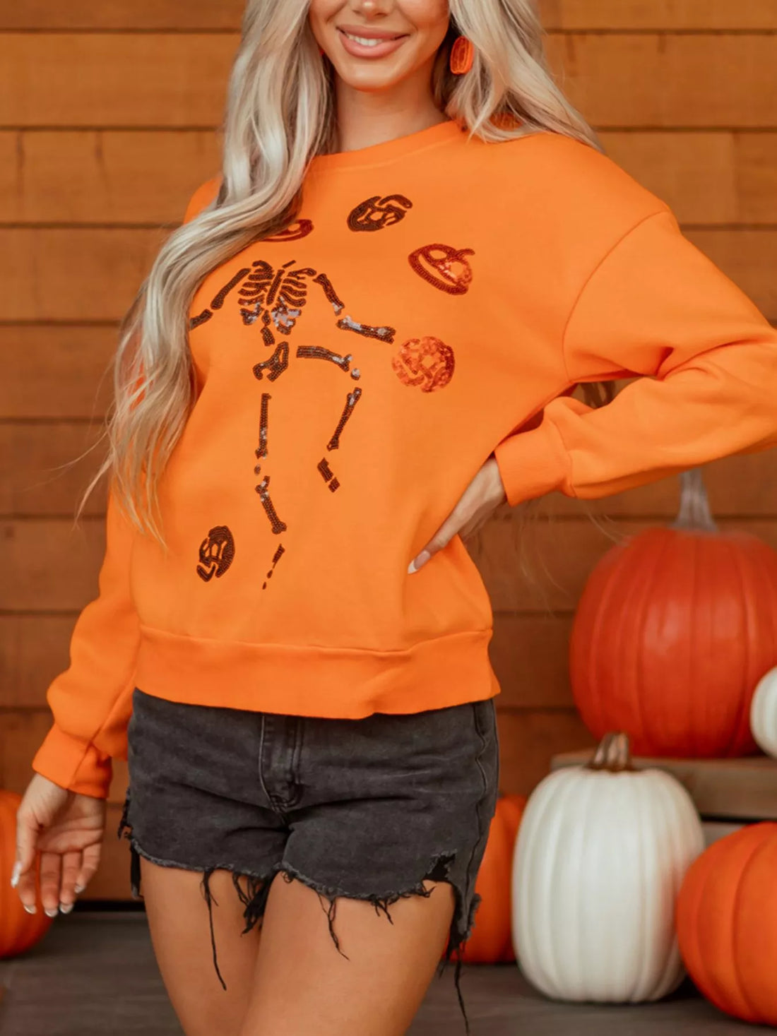 Orange crewneck sweatshirt with sequin skeleton and spooky icon graphic front