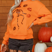 Orange crewneck sweatshirt with sequin skeleton and spooky icon graphic front