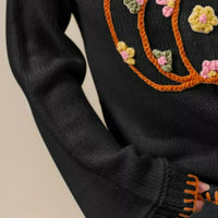 Black knit sweater sleeve with orange stitched trim and ribbed cuff